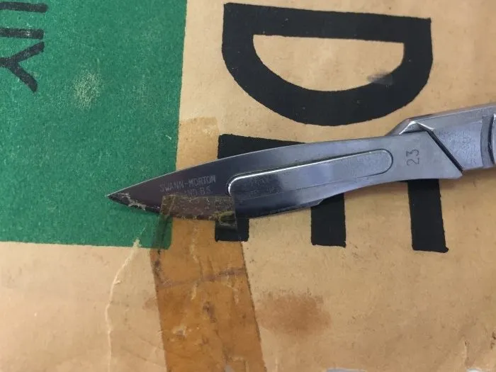 Retrait au scalpel d'un ancien ruban adhésif sur l'affiche